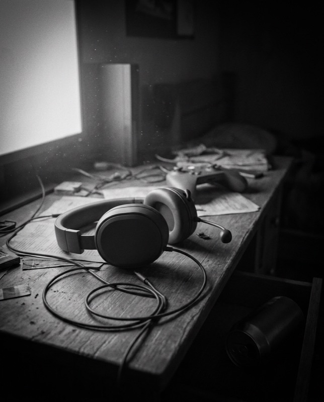 An abandoned gaming headset on a desk lit by monitor glow