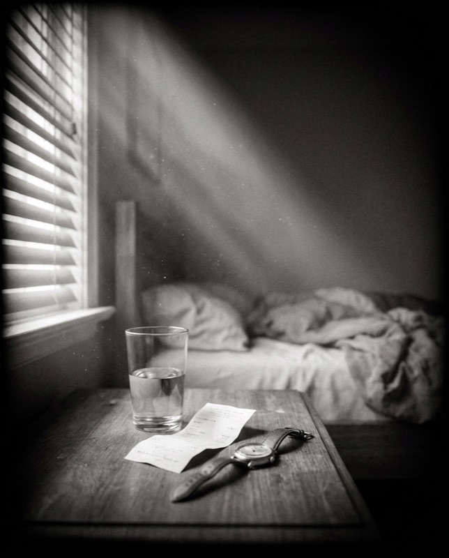 A glass of water and a crumpled receipt on a nightstand
