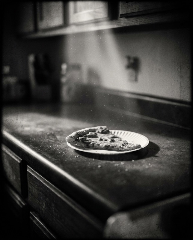 A half-eaten slice of pizza late at night